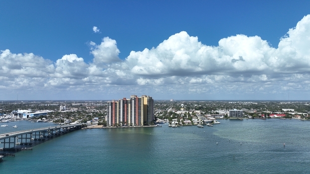 Aerial view of the multi story building reflecting the sunlight alongside a bridge over the water West Palm Beach Florida United States.