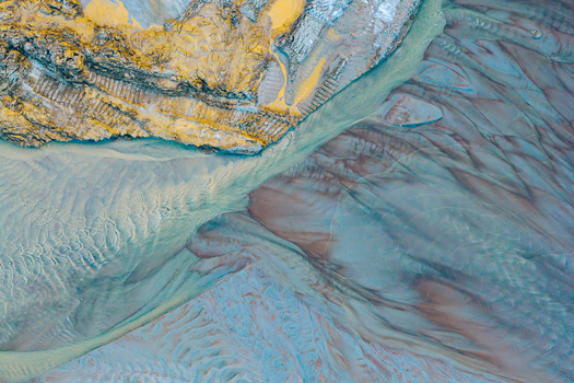 Aerial view of abstract textures in a gravel and sand mine with sediment patterns and water flow in Poland.