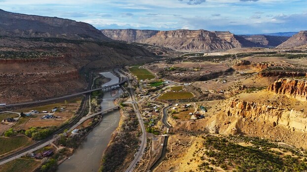 Aerial view of the river winding through the rugged canyons a tapestry of ochre cliffs and verdant fields contrasting under the expansive sky Palisade Colorado USA. Aerial view of the river winding through the rugged canyons a tapestry of ochre cliffs and verdant fields contrasting under the expansive sky Palisade Colorado USA.