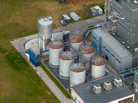 Aerial view of industrial facility with multiple large metal storage silos and adjacent factory buildings situated in a green landscape Breclav South Moravian Region Czechia.