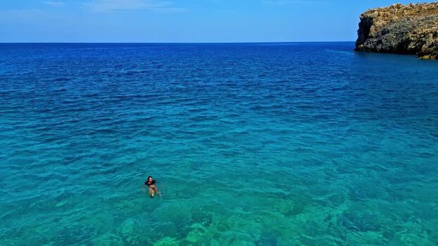 Aerial view of a person swimming in turquoise waters Greece.