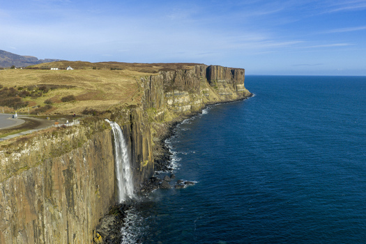 Aerial view of Kilt Rock and Mealt Falls cascading down basalt cliffs into the blue sea under a clear sky Isle of Skye Scotland United Kingdom. Aerial view of Kilt Rock and Mealt Falls cascading down basalt cliffs into the blue sea under a clear sky Isle of Skye Scotland United Kingdom.