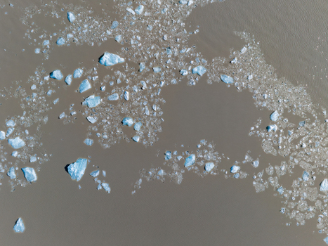 Aerial view of icebergs floating in the murky waters of a glacial lagoon in Iceland. Aerial view of icebergs floating in the murky waters of a glacial lagoon in Iceland.