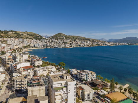Aerial view of the coastal city of Saranda nestled along the Ionian Sea with white buildings hills and a clear blue sky in Saranda Vlore County Albania. Aerial view of the coastal city of Saranda nestled along the Ionian Sea with white buildings hills and a clear blue sky in Saranda Vlore County Albania.