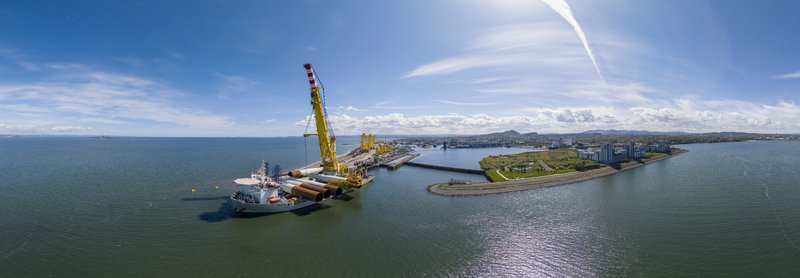 Edinburgh United Kingdom 06 May 2026 Aerial view of Leith docks featuring a heavy lift vessel with a large yellow crane and wind turbine components under a bright blue sky. Edinburgh United Kingdom 06 May 2026 Aerial view of Leith docks featuring a heavy lift vessel with a large yellow crane and wind turbine components under a bright blue sky.