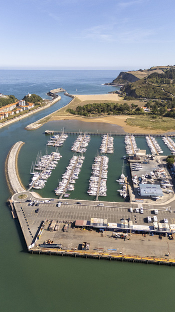 Aerial view of the marina in Zumaia with numerous boats docked in rows a concrete pier and a sandy beach along the coastline in Zumaia Basque Country Spain.