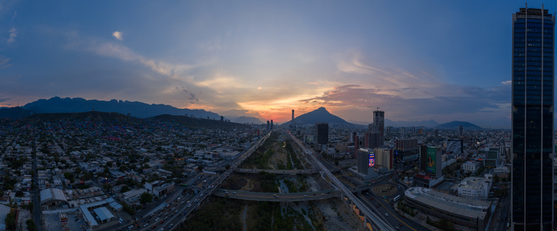 Aerial view of the Monterrey cityscape at sunset with modern skyscrapers the Santa Catarina River and the Cerro de la Silla mountain in the background in Monterrey Nuevo Leon Mexico. Aerial view of the Monterrey cityscape at sunset with modern skyscrapers the Santa Catarina River and the Cerro de la Silla mountain in the background in Monterrey Nuevo Leon Mexico.