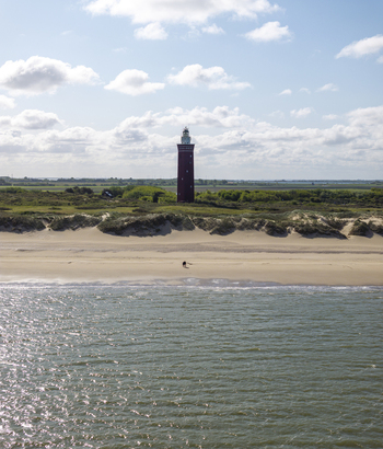 Aerial view of Westhoofd Lighthouse standing behind sandy dunes and a beach with the North Sea in the foreground under a bright blue sky in Ouddorp Zuid Holland Netherlands. Aerial view of Westhoofd Lighthouse standing behind sandy dunes and a beach with the North Sea in the foreground under a bright blue sky in Ouddorp Zuid Holland Netherlands.