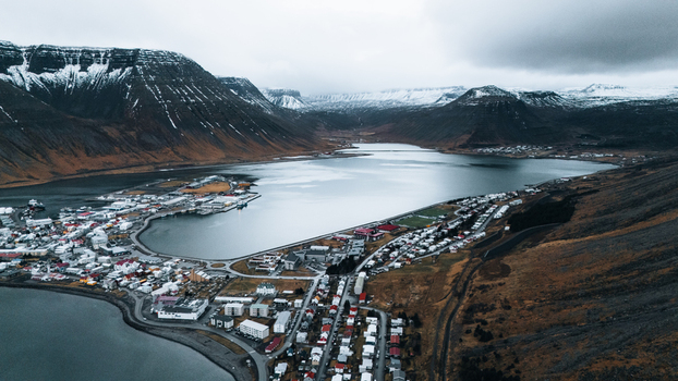 Aerial view of a town nestled on the edge of a tranquil fjord where buildings meet the water s edge under a sky heavy with clouds Ísafjörður Iceland. Aerial view of a town nestled on the edge of a tranquil fjord where buildings meet the water s edge under a sky heavy with clouds Ísafjörður Iceland.