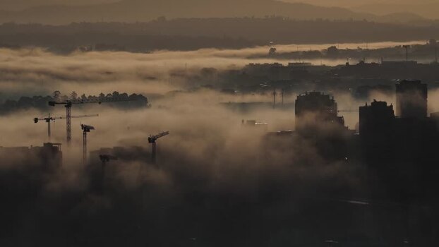 Aerial view of buildings and cranes in fog Portugal.