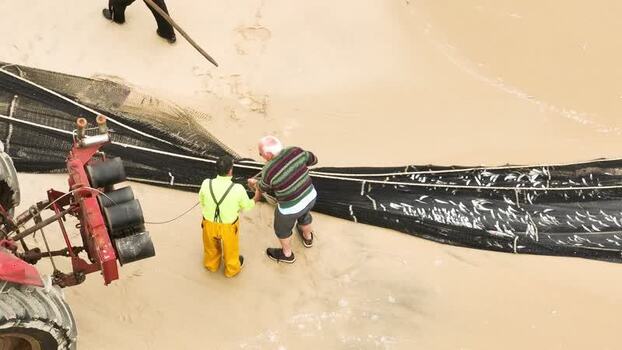 Aerial view of fishermen pulling nets on the beach Portugal. Aerial view of fishermen pulling nets on the beach Portugal.