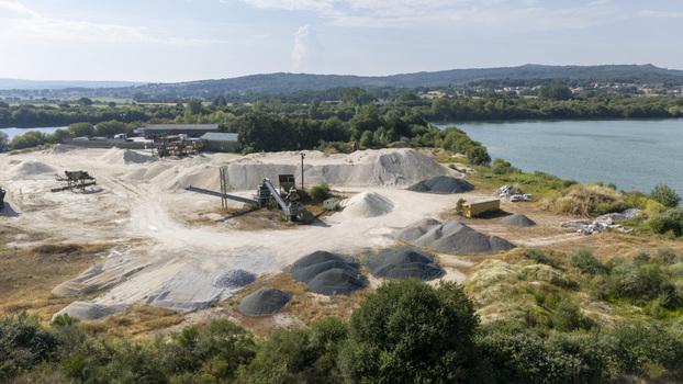 Aerial view of the Extraccion de aridos Lima S.L industrial site with piles of sand gravel and machinery along the riverbank in Vilarino das Poldras Ourense Spain. Aerial view of the Extraccion de aridos Lima S.L industrial site with piles of sand gravel and machinery along the riverbank in Vilarino das Poldras Ourense Spain.