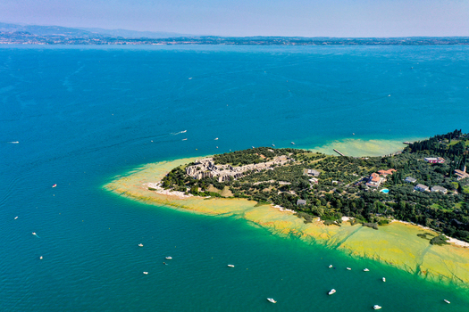 Aerial view of the Grotte di Catullo ruins at the tip of the peninsula surrounded by the turquoise waters of Lake Garda Sirmione Lombardia Italy. Aerial view of the Grotte di Catullo ruins at the tip of the peninsula surrounded by the turquoise waters of Lake Garda Sirmione Lombardia Italy.