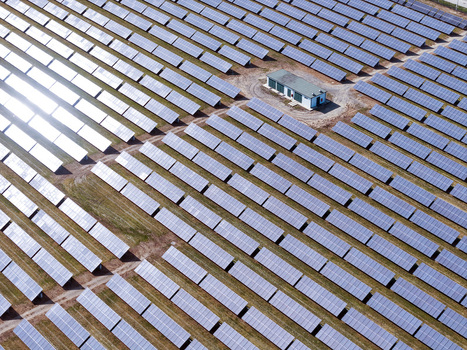 Aerial view of rows of solar panels in a large photovoltaic power plant with a small utility building under bright sunlight Torrazza Piemonte Piemonte Italy. Aerial view of rows of solar panels in a large photovoltaic power plant with a small utility building under bright sunlight Torrazza Piemonte Piemonte Italy.