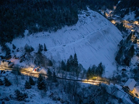 Aerial view of Spania Dolina village with snowy slopes and illuminated houses nestled in a dark evergreen forest at night Spania Dolina Banska Bystrica Regio Slovakia. Aerial view of Spania Dolina village with snowy slopes and illuminated houses nestled in a dark evergreen forest at night Spania Dolina Banska Bystrica Regio Slovakia.