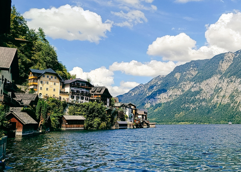 View of the historic village of Hallstatt with traditional alpine houses nestled along the shore of Hallstatter See under a bright blue sky in Hallstatt Upper Austria Austria. View of the historic village of Hallstatt with traditional alpine houses nestled along the shore of Hallstatter See under a bright blue sky in Hallstatt Upper Austria Austria.