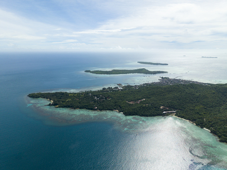 Aerial view of a vibrant island fringed with turquoise waters meeting the deep blue sea under a soft sky Karimunjawa Central Java Indonesia.