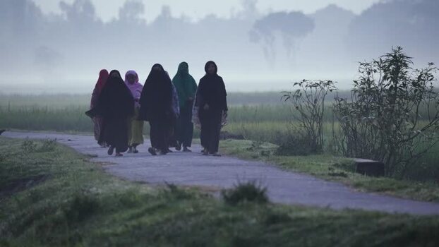 View of women walking on a rural path in the mist Bangladesh.