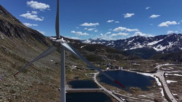 Aerial view of a wind turbine at San Gottardo wind Park overlooking mountain lakes and snow capped peaks in the Swiss Alps Airolo Ticino Switzerland.
