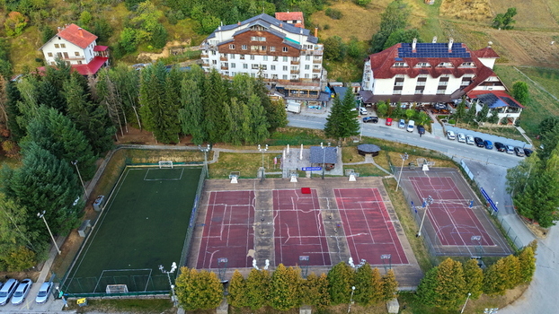 Aerial view of Brzece Sports Centar featuring a soccer field multiple tennis courts and a basketball court surrounded by hotels and lush trees in Brzece Rasina District Serbia.