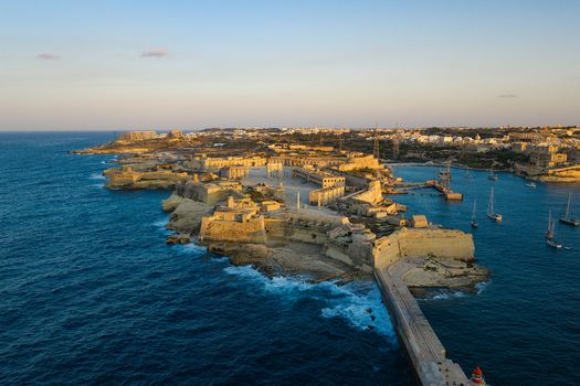 Aerial view of the historic Fort Ricasoli surrounded by the deep blue waters of the Grand Harbour with sailboats and stone fortifications in Valletta Port Region Malta. Aerial view of the historic Fort Ricasoli surrounded by the deep blue waters of the Grand Harbour with sailboats and stone fortifications in Valletta Port Region Malta.