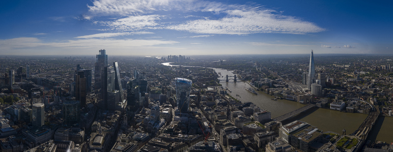 Aerial view of the City of London skyline with the River Thames Tower Bridge and modern skyscrapers under a bright blue sky in London England United Kingdom.