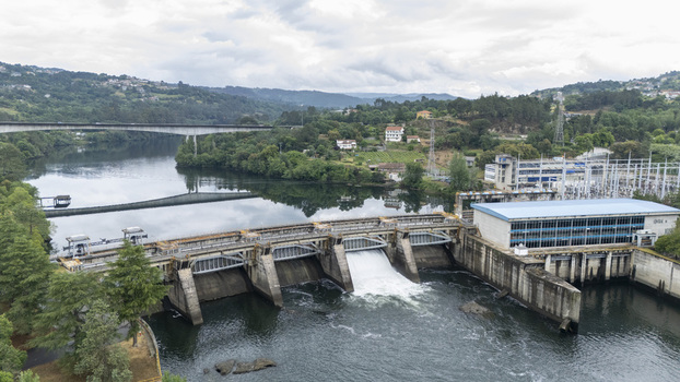 Aerial view of the Velle hydroelectric dam and power substation with water flowing through the gates on the Minho River surrounded by green hills in Ourense Ourense Spain.