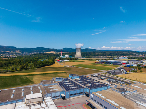 Aerial view of an industrial facility with solar panels and the Gosgen Nuclear Power Plant in the background surrounded by fields and hills in Daniken Solothurn Switzerland.