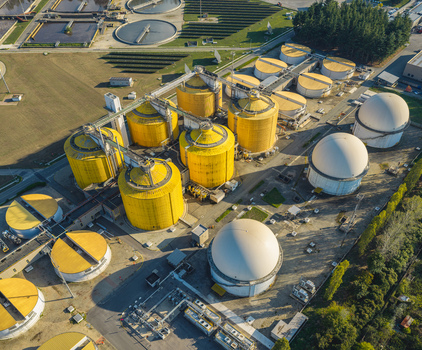 Aerial view of anaerobic digesters biogas storage domes and wastewater treatment infrastructure at an environmental facility in Italy.