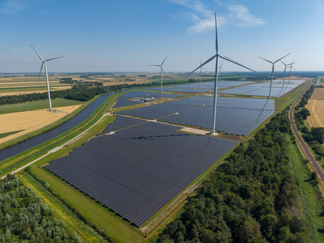 Aerial view of a large solar farm with wind turbines in a rural landscape in the Netherlands.