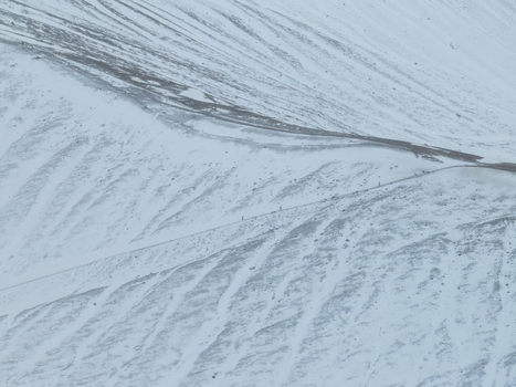 Aerial view of Hverfjall volcanic crater rim covered in snow with hikers walking along the ridge path in Thingeyjarsveit Iceland. Aerial view of Hverfjall volcanic crater rim covered in snow with hikers walking along the ridge path in Thingeyjarsveit Iceland.