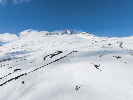 Aerial view of the snow covered south side of Mount Etna with volcanic rock ridges under a clear blue sky in Nicolosi Sicilia Italy. Aerial view of the snow covered south side of Mount Etna with volcanic rock ridges under a clear blue sky in Nicolosi Sicilia Italy.