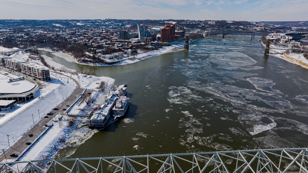 Aerial view of the Ohio River filled with ice floes and snow covered banks near the Cincinnati skyline and historic bridges in Cincinnati Ohio United States. Aerial view of the Ohio River filled with ice floes and snow covered banks near the Cincinnati skyline and historic bridges in Cincinnati Ohio United States.