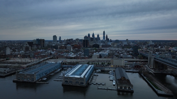Aerial view of the Delaware River reflecting the city skyline and the Benjamin Franklin Bridge under a muted sky Philadelphia Pennsylvania United States.