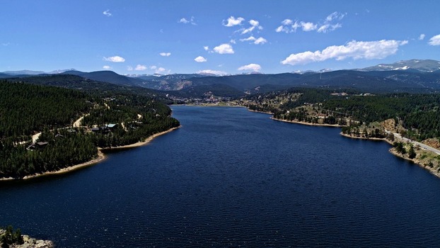 Aerial view of Barker Meadow Reservoir surrounded by dense pine forests and rolling mountains under a clear blue sky in Boulder County Colorado United States. Aerial view of Barker Meadow Reservoir surrounded by dense pine forests and rolling mountains under a clear blue sky in Boulder County Colorado United States.