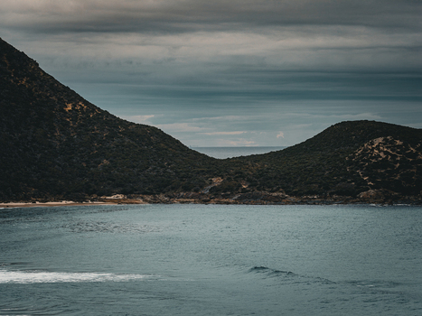 Aerial view of Conspicuous Cliff featuring rugged coastal hills dark green vegetation and calm ocean waters under a moody overcast sky in Nornalup Western Australia Australia. Aerial view of Conspicuous Cliff featuring rugged coastal hills dark green vegetation and calm ocean waters under a moody overcast sky in Nornalup Western Australia Australia.