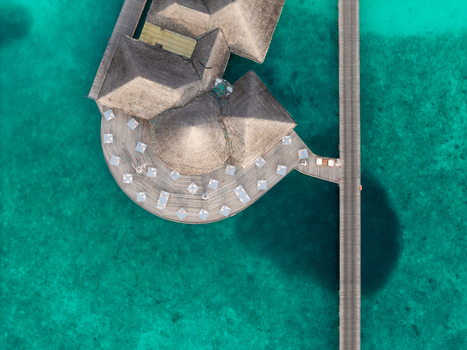 Aerial view of thatched roofs and sun kissed decks meet the turquoise embrace of the ocean connected by a sleek wooden walkway Hoarafushi Maldives. Aerial view of thatched roofs and sun kissed decks meet the turquoise embrace of the ocean connected by a sleek wooden walkway Hoarafushi Maldives.