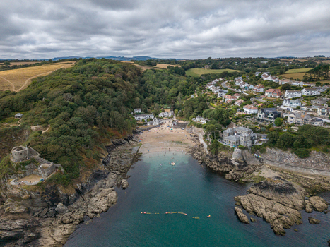 Aerial view of Readymoney Cove with its sandy beach rocky cliffs and St Catherine s Castle ruins surrounded by houses and greenery in Fowey Cornwall United Kingdom. Aerial view of Readymoney Cove with its sandy beach rocky cliffs and St Catherine s Castle ruins surrounded by houses and greenery in Fowey Cornwall United Kingdom.