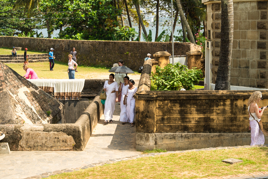 Galle Sri Lanka 04 February 2026 View of people walking along the historic stone ramparts of Galle Fort with palm trees and the ocean in the background.