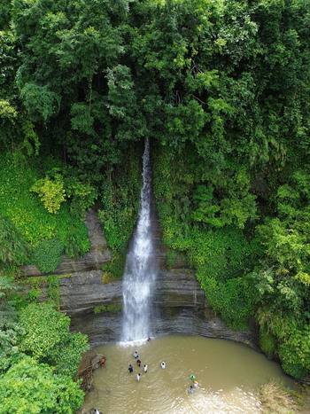 Aerial view of the Sitakund waterfall cascading into a natural pool surrounded by dense green forest with people swimming in the water in Sitakund Chittagong Division Bangladesh. Aerial view of the Sitakund waterfall cascading into a natural pool surrounded by dense green forest with people swimming in the water in Sitakund Chittagong Division Bangladesh.