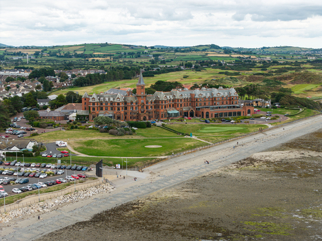 Aerial view of the historic Slieve Donard Hotel with its red brick architecture surrounded by green lawns and adjacent to the beach in Newcastle Northern Ireland United Kingdom. Aerial view of the historic Slieve Donard Hotel with its red brick architecture surrounded by green lawns and adjacent to the beach in Newcastle Northern Ireland United Kingdom.