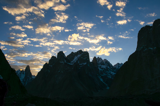 View of Trango Towers mountain range under a dramatic sunset sky with scattered clouds in Gilgit Baltistan Pakistan. View of Trango Towers mountain range under a dramatic sunset sky with scattered clouds in Gilgit Baltistan Pakistan.