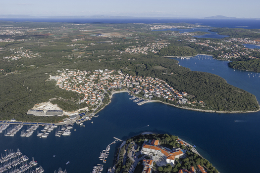 Aerial view of Pjescana Uvala featuring a coastal village with terracotta rooftops a marina and lush forests along the Adriatic Sea in Pula Pjescana Uvala Istarska zupanija Croatia.