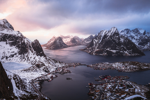 Aerial view of snow dusted peaks rise majestically over the tranquil waters surrounding Reinebringen Nordland Norway.