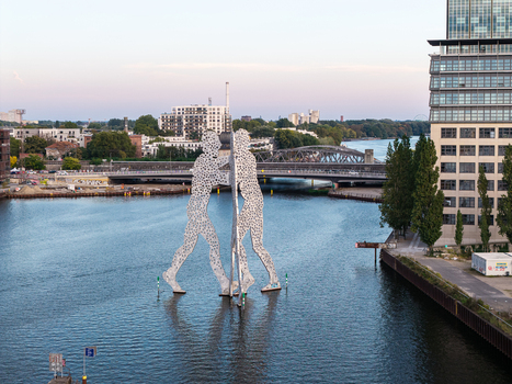Aerial view of the Molecule Men sculpture standing in the Spree river with a bridge and modern architecture in the background in Berlin Berlin Germany. Aerial view of the Molecule Men sculpture standing in the Spree river with a bridge and modern architecture in the background in Berlin Berlin Germany.