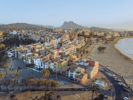 Aerial view of the colorful houses along the coastline with a sandy beach and mountains under a clear sky in La Vila Joiosa Valencian Community Spain. Aerial view of the colorful houses along the coastline with a sandy beach and mountains under a clear sky in La Vila Joiosa Valencian Community Spain.