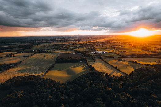 Aerial view of Cannock Chase Forest at sunset with rolling fields lush woodland and dramatic clouds over the countryside in Staffordshire England United Kingdom. Aerial view of Cannock Chase Forest at sunset with rolling fields lush woodland and dramatic clouds over the countryside in Staffordshire England United Kingdom.