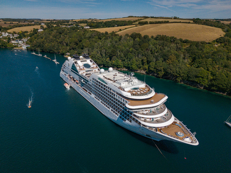 Fowey United Kingdom 10 August 2026 Aerial view of a large cruise ship anchored in the Fowey River surrounded by lush green hills and small boats in the water. Fowey United Kingdom 10 August 2026 Aerial view of a large cruise ship anchored in the Fowey River surrounded by lush green hills and small boats in the water.