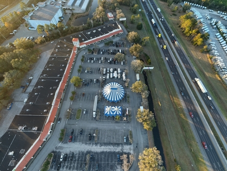 Aerial view of a blue and white circus tent pitched in a parking lot adjacent to a bustling highway casting long shadows in the soft light St. Augustine Florida United States. Aerial view of a blue and white circus tent pitched in a parking lot adjacent to a bustling highway casting long shadows in the soft light St. Augustine Florida United States.