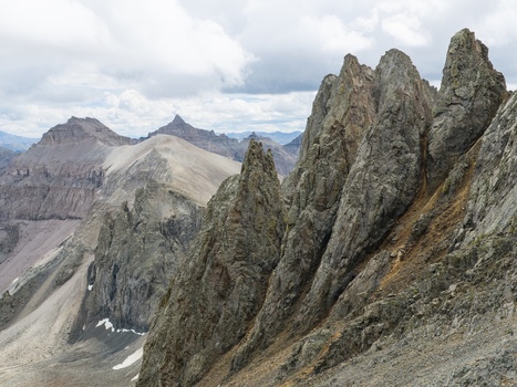 Aerial view of the jagged rocky peaks of Mount Sneffels in the San Juan Mountains with steep slopes and patches of snow in Ouray County Colorado United States. Aerial view of the jagged rocky peaks of Mount Sneffels in the San Juan Mountains with steep slopes and patches of snow in Ouray County Colorado United States.